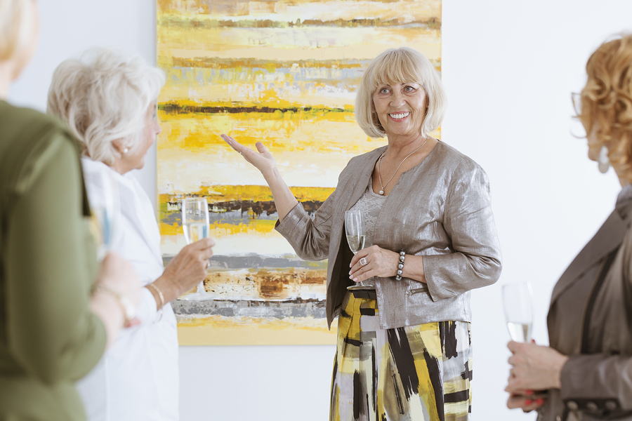 Happy elderly woman presenting the painting in art gallery