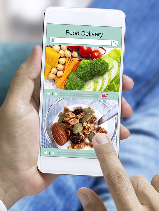 Online order food and express delivery service food shopping concept on touch screen which hand's man holding smart phone lying on sofa at home background.